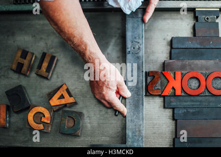 Detail of hand using letterpress machine in book arts workshop, overhead view Stock Photo