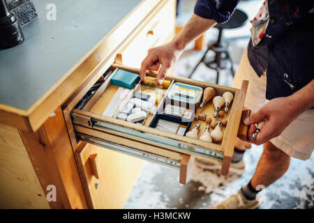 Hand reaching into open drawer containing equipment and materials in book arts workshop Stock Photo