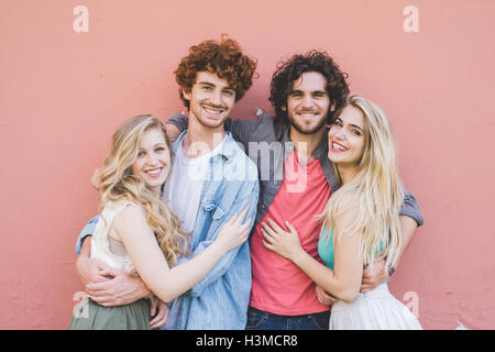 Couples hugging against pink wall background Stock Photo