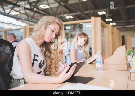 Co-workers working on digital tablet in open plan office Stock Photo