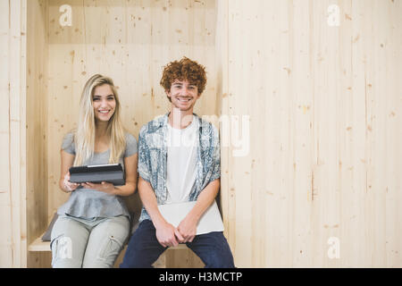 Co-workers using digital tablet in wooden panelled seating area Stock Photo