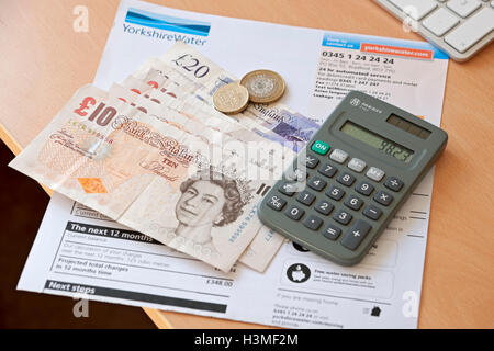 Close up of domestic water bill household bills calculator and cash money payment England UK United Kingdom GB Great Britain Stock Photo