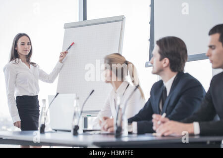 Business woman speaking at presentation and pointing to white board Stock Photo