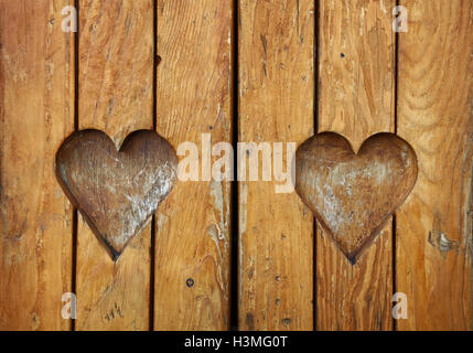 Two heart shaped elements, symbol of love, romance and togetherness, wood carved cut in vintage old grunge natural brown wooden Stock Photo