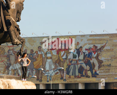 Young woman poses with the Skanderberg Monument in Tirana's Skanderberg Square. Stock Photo