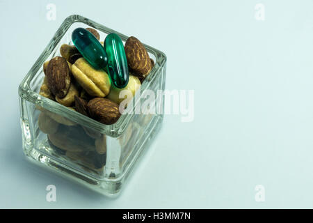 2 capsules on top of mixed nuts in a glass container Stock Photo
