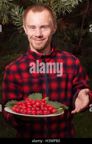 young man with the fruit of hawthorn Stock Photo