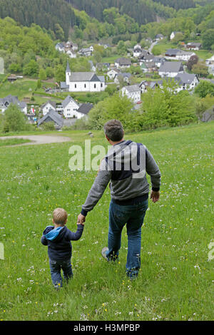 father and his little son walking through a meadow Stock Photo