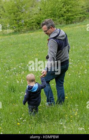 father and his little son walking through a meadow Stock Photo