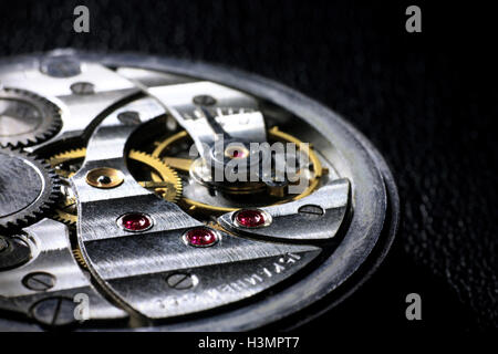 Pocket watch inside close up with wheels, springs and rubies on dark background Stock Photo