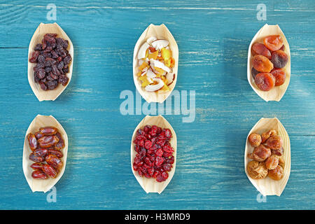 Dried fruits selection in wooden bowls on blue rustic table, view from above. Stock Photo