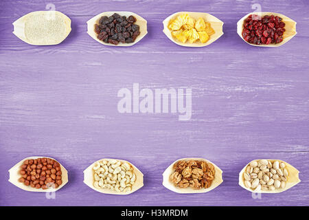 Nuts and dried fruits selection in wooden bowls on rustic table, view from above, space for text. Stock Photo