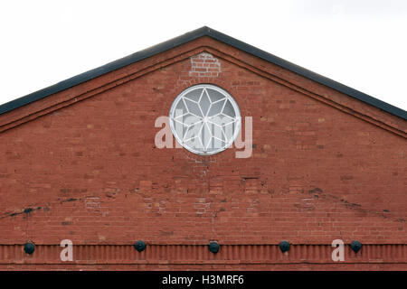 Crest of an old building with round window. Building made of bricks. Stock Photo