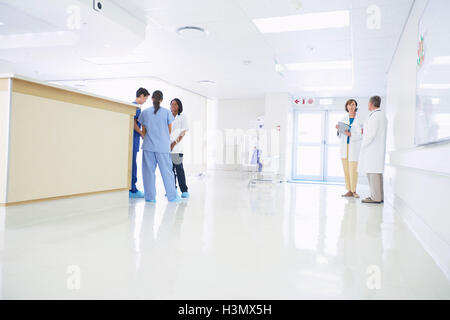 Doctors and nurses talking by nurses station in hospital Stock Photo