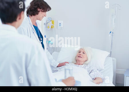 Doctors explaining to senior female patient in hospital bed Stock Photo