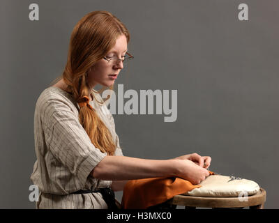 Young female designer sewing fabric on cushion Stock Photo