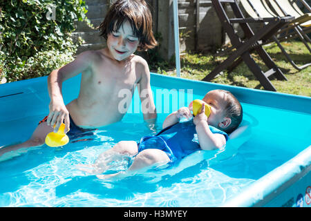 Happy brothers playing in inflatable pool on summer day Stock Photo