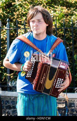 Young Caucasian man, 20s, from the Royal Liberty Morris side, standing outdoors playing accordion. Close up, half length. Broadstairs Folk Week. Stock Photo