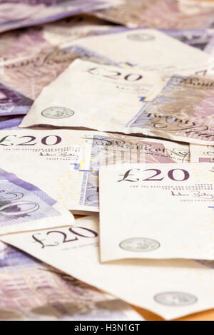 Deep focus view along British £20, twenty pound notes scattered showing £20 logo. Stock Photo