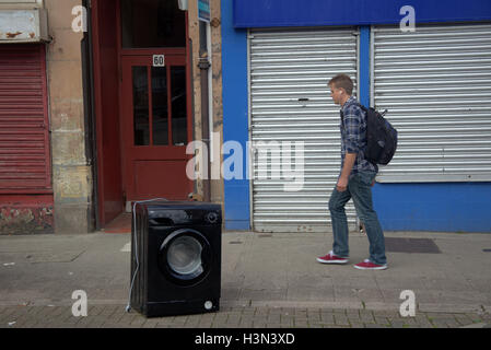 Glasgow street scenes Glasgow street scenes tourist young man encounters discarded black washing machine metaphor Stock Photo