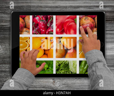 child hands touching  tablet computer screen with mixed fruit picture Stock Photo