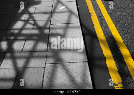 Double yellow lines on a shadowy street Stock Photo