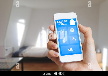 Smart home automation app on smartphone hold by female’s hand with home interior in background Stock Photo