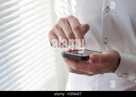 Young adult using smartphone with bright office background Stock Photo