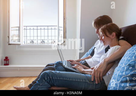 Happy couple watching video with computer on couch Stock Photo