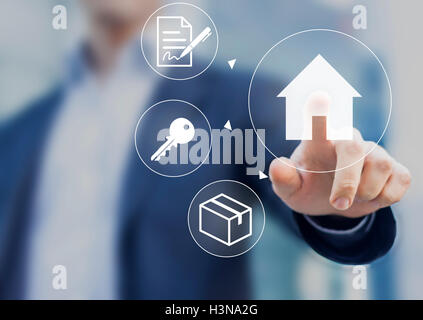 Hand pushing house button on screen with mortgage contract, keys and boxes Stock Photo