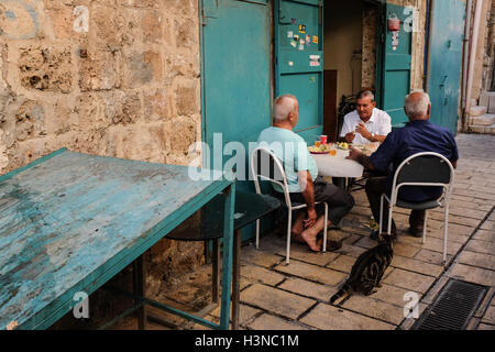 Acre, Israel. 10th October, 2016. Men enjoy an outdoor lunch in a narrow alley of Acre's Old City. Credit:  Nir Alon/Alamy Live News Stock Photo