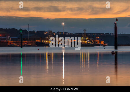 Milford Haven, Pembrokeshire, UK. 11th October, 2016. A cold and crisp October day got even more chilly as the sun set and the moon rose over Milford Haven. Tractors made their way back across the Cleddau Bridge, with the Valero Oil Refinery in the background. A mix of agriculture and industry in Pembrokeshire. Credit:  Derek Phillips/Alamy Live News Stock Photo