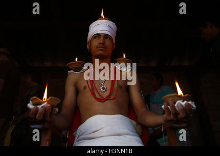 Bhaktapur, Nepal. 11th Oct, 2016. A devotee sits with lit oil lamps on his shoulders while offering prayers during Dashain, a Hindu religious festival in Bhaktapur. © Skanda Gautam/ZUMA Wire/Alamy Live News Stock Photo