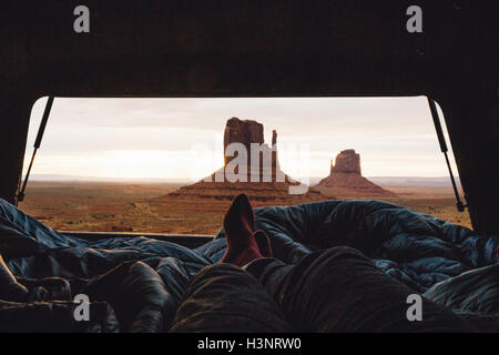 Male legs and feet relaxing inside four wheel drive with view of sandstone buttes from car boot, Monument Valley, Arizona, USA Stock Photo