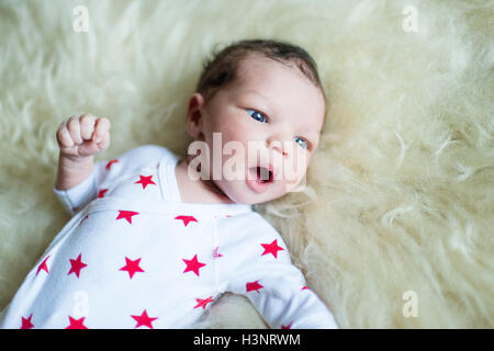 New born baby boy lying on fluffy blanket looking away Stock Photo