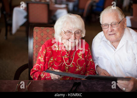 Portrait of senior couple sitting at table in restaurant, smiling Stock Photo