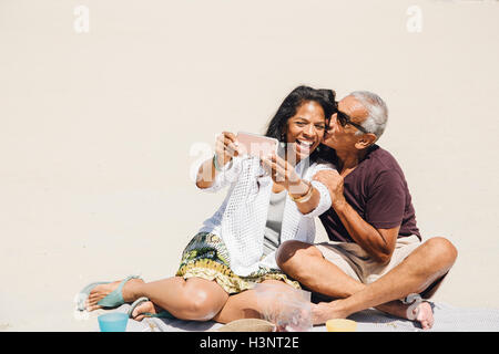 Senior couple sitting on beach, taking selfie with smartphone, Long Beach, California, USA Stock Photo