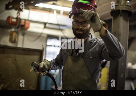 Welder holding welding torch looking at camera