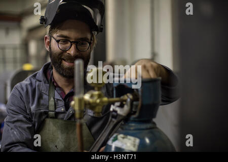 Welder looking at gas canister smiling