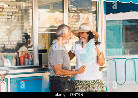 Senior couple standing beside refreshment stand, holding cotton candy, Long Beach, California, USA Stock Photo