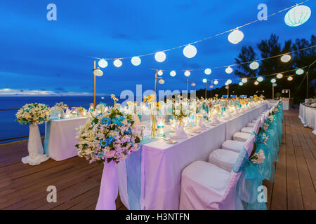 Romantic dinner setup, White and Blue theme decorated with candle light, lanterns and flowers. Selective focus. Stock Photo
