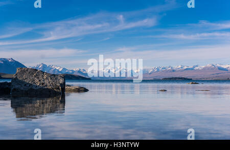 Panorama of Lake Tekapo with rock reflection and snow mountain range in the background Stock Photo