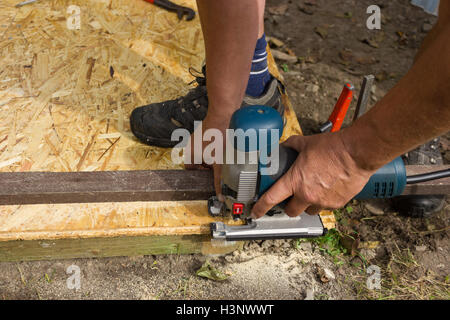 Men using an electric saw to cut a plank Stock Photo