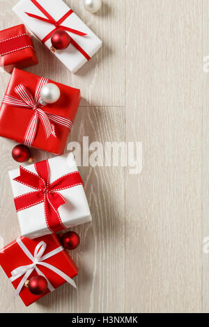 Christmas gifts presents on rustic wood background. Red and white wrapped gift boxes with ribbon bows. Stock Photo