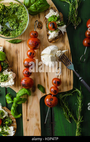 Grilled toasts with mozzarella, tomatoes and homemade pesto, vegetable on skewers Stock Photo