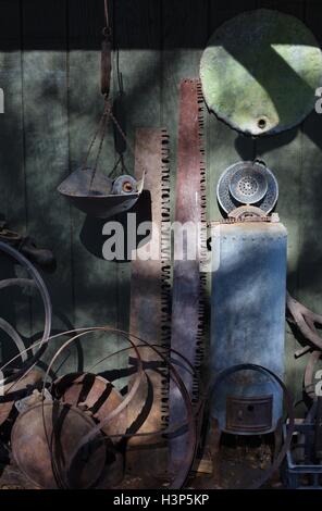 Rusty old antique tools and metal objects next to a rustic barn. Stock Photo