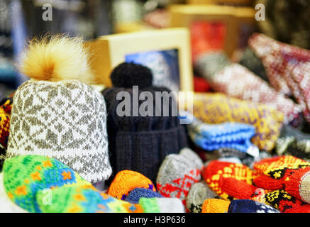 Two warm hats among other knitted clothes displayed for sale at the Christmas market in old Riga, Latvia. At this stand people can also buy festive mittens, gloves, scarfs and little toys for kids. Stock Photo