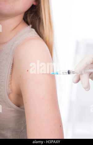 MODEL RELEASED. Teenage girl having injection in arm. Stock Photo