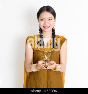 Mixed race Indian Chinese woman in traditional dress hands holding diya oil lamp and celebrating Diwali or deepavali, fesitval o Stock Photo