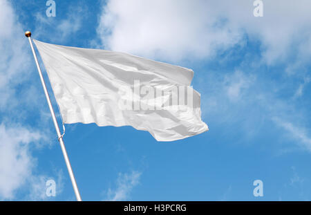 White flag waving in the wind against cloudy sky. Perfect mock up to add any logo, symbol or sign Stock Photo